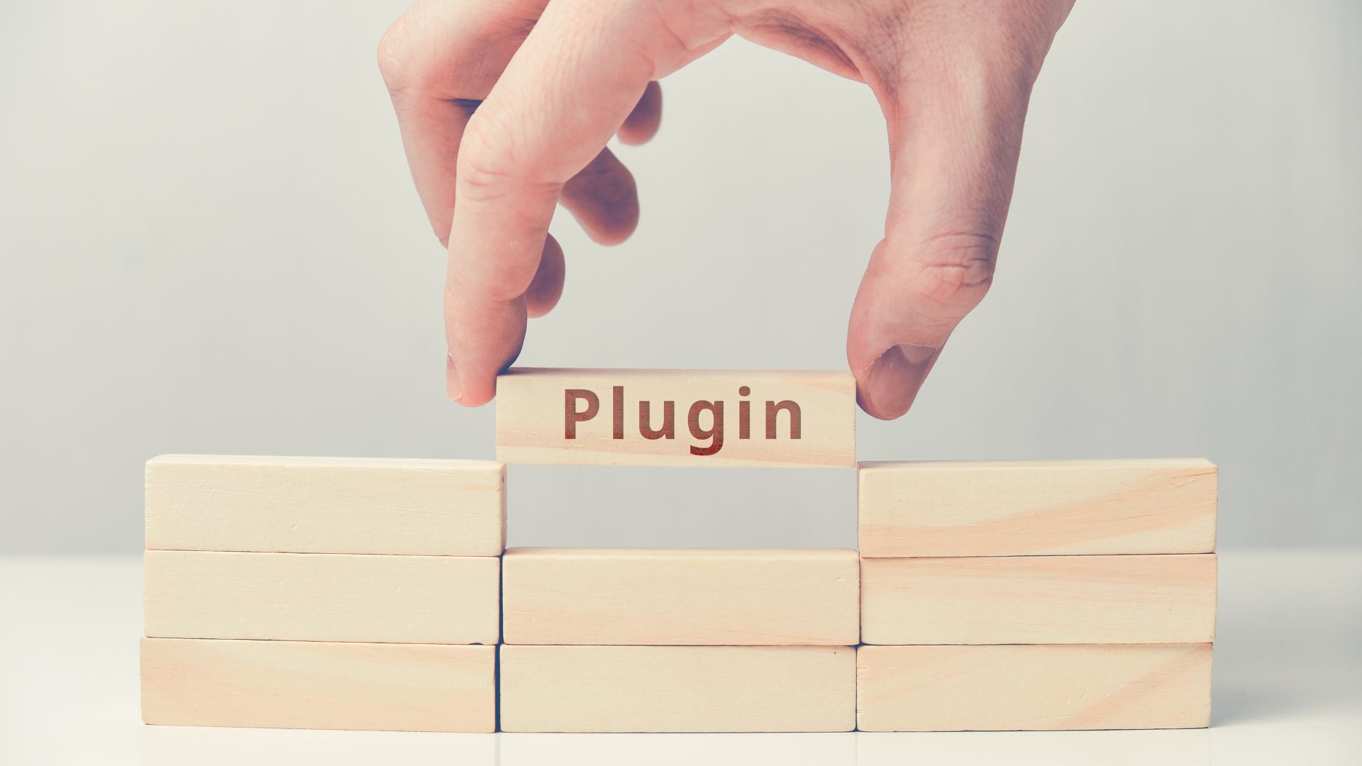 Hand placing a wooden block labeled “Plugin” between others, symbolising plugin dependency and structure.